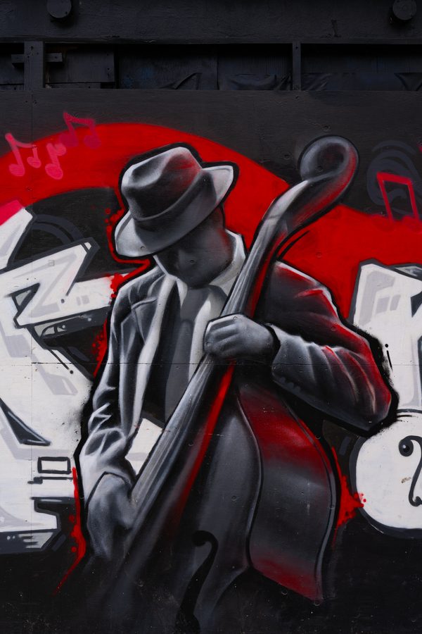Fresque de street art à San Francisco : contrebassiste de jazz au chapeau feutre en noir et blanc, ruban rouge et notes de musique